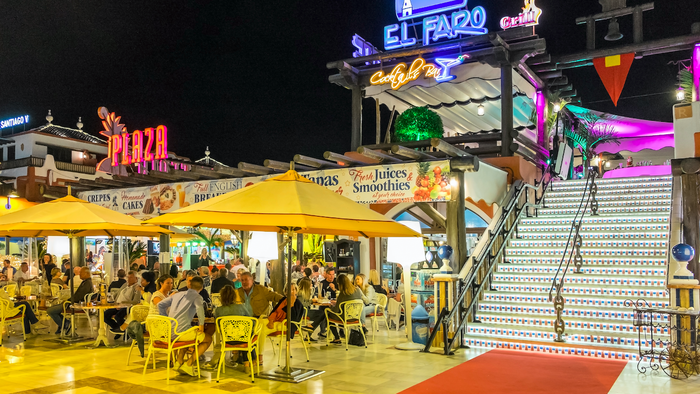 Nightlife in the bars and terraces of a modern shopping center in the tourist city of Playa de las Americas