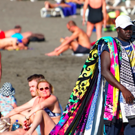 Man walking along the beach selling beach towels and blankets