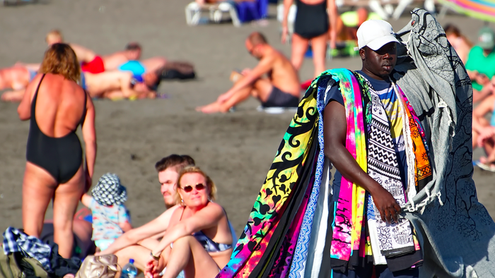 Man walking along the beach selling beach towels and blankets