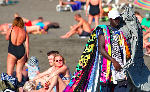 Man walking along the beach selling beach towels and blankets