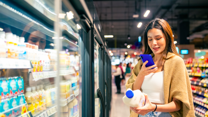 Woman at a supermarket scanning code with her mobile phone