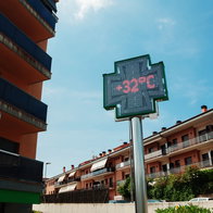 Digital street temperature display showing 32C during hot weather in a residential area in Spain.