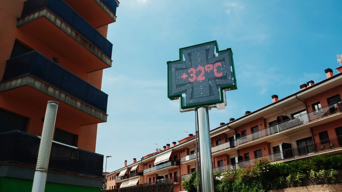 Digital street temperature display showing 32C during hot weather in a residential area in Spain.