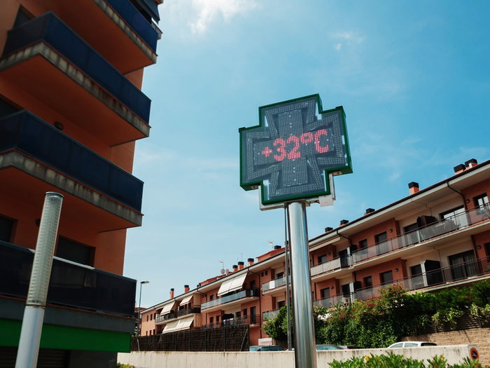 Digital street temperature display showing 32C during hot weather in a residential area in Spain.