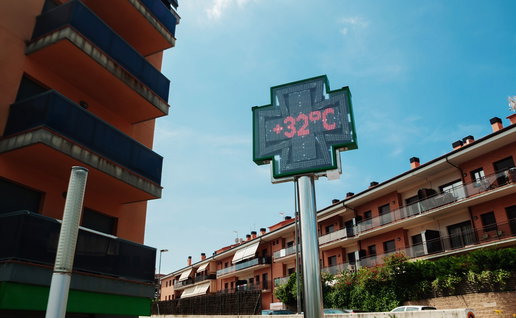 Digital street temperature display showing 32C during hot weather in a residential area in Spain.