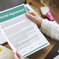 A landlord reviews a rental agreement at home while checking documents before signing a tenancy contract.