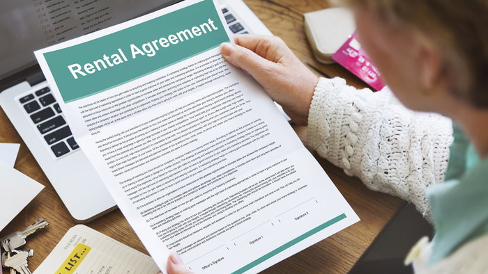 A landlord reviews a rental agreement at home while checking documents before signing a tenancy contract.