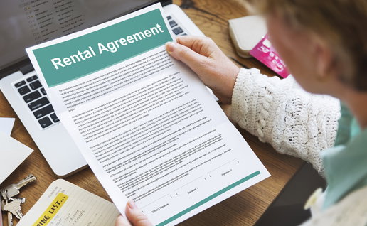 A landlord reviews a rental agreement at home while checking documents before signing a tenancy contract.