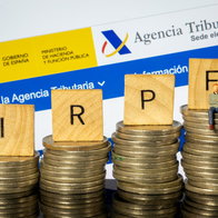 Spanish Tax Agency website displayed behind stacks of coins and IRPF tax blocks
