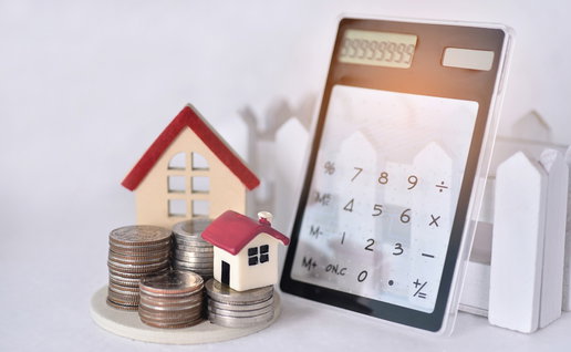 Calculator, coins and miniature houses symbolising rental deposits and housing costs in Spain.