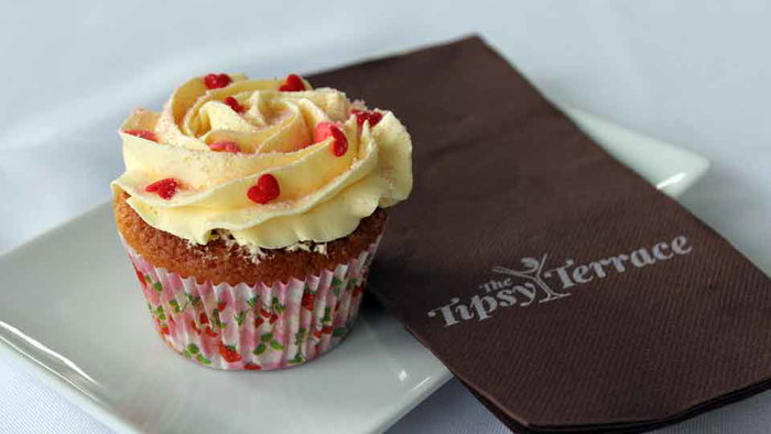 A cake on a plate with a serviette that says "Tipsy Terrace".
