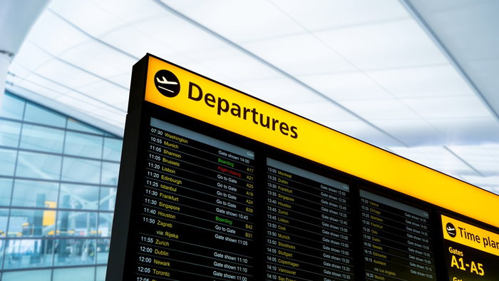 Airport departures board showing flight schedules and status updates inside a UK terminal