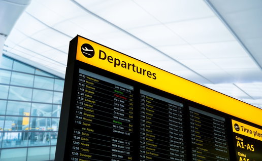 Airport departures board showing flight schedules and status updates inside a UK terminal
