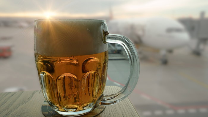 Beer served inside an airport terminal with a passenger plane blurred in the background