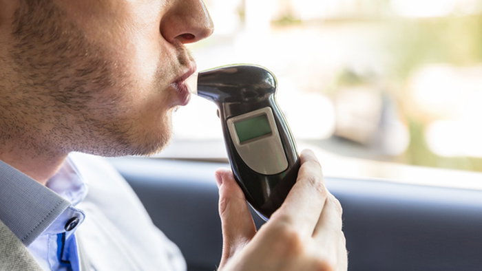 Passenger blowing into breathalyser during roadside alcohol test in Spain