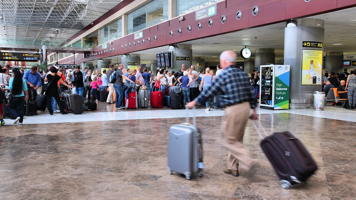 Long queues of travellers waiting at border control in a busy Spanish airport terminal