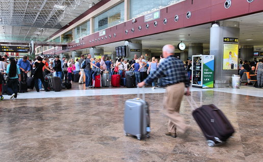 Long queues of travellers waiting at border control in a busy Spanish airport terminal