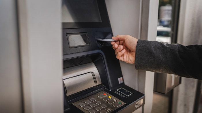 Person using a bank card at a traditional ATM cash machine.