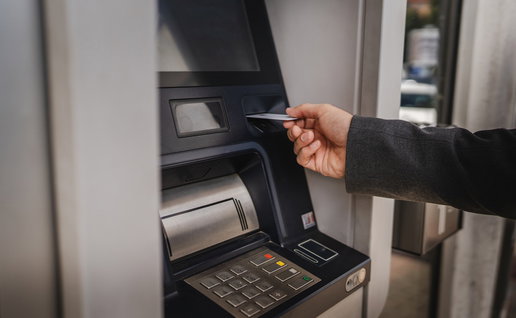 Person using a bank card at a traditional ATM cash machine.
