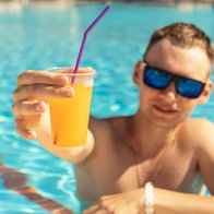 Man drinking cocktail in swimming pool