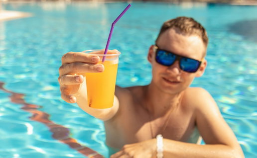 Man drinking cocktail in swimming pool