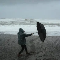 woman on beach with umbrella in wind
