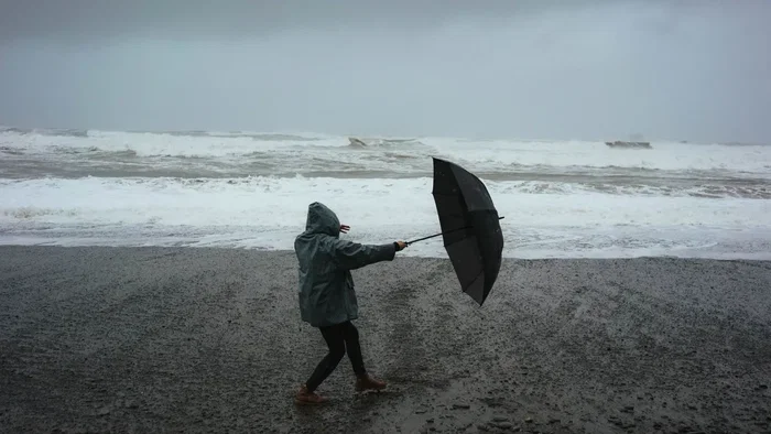 woman on beach with umbrella in wind
