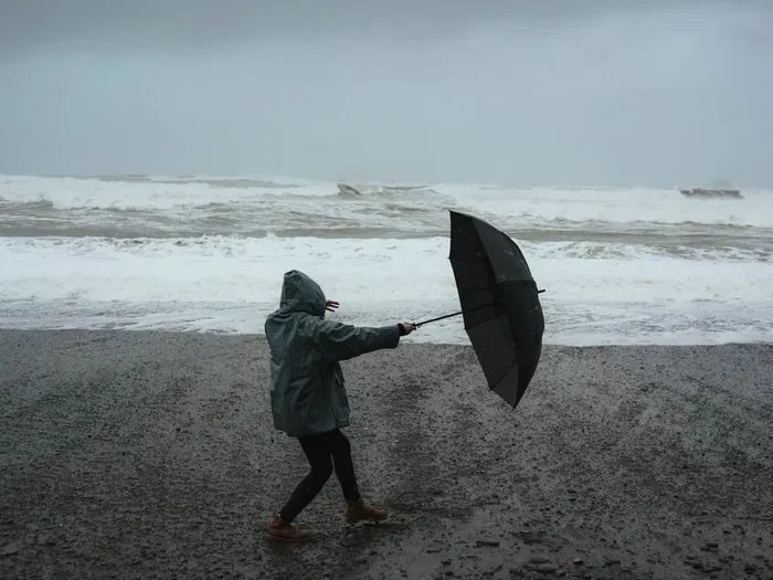 woman on beach with umbrella in wind