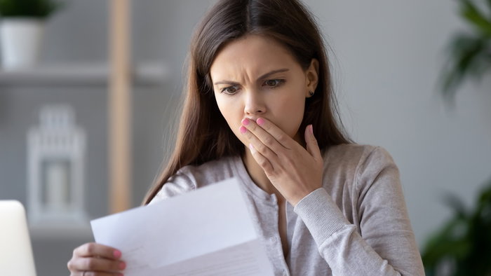 Woman looks shocked while reading a letter as Hacienda prepares to send warning notices over tax return mistakes in Spain.