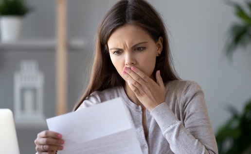 Woman looks shocked while reading a letter as Hacienda prepares to send warning notices over tax return mistakes in Spain.