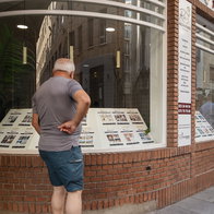Man looking at property listings in a real estate agency window in Spain
