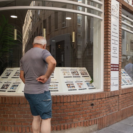Man looking at property listings in a real estate agency window in Spain