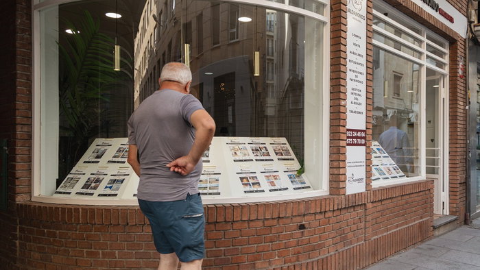Man looking at property listings in a real estate agency window in Spain
