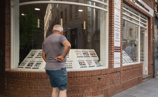 Man looking at property listings in a real estate agency window in Spain