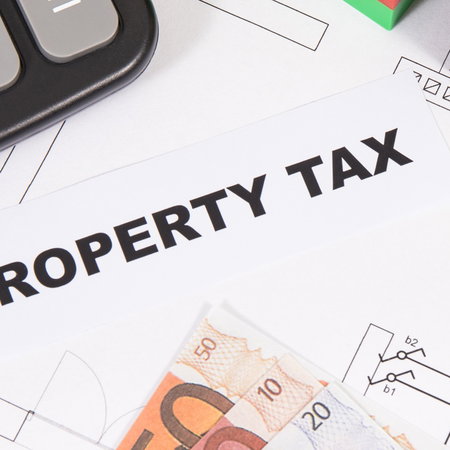 Property tax paperwork and euro banknotes illustrating rising housing costs and IBI charges in Spain.