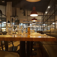 Interior of a modern restaurant in Spain with visible ceiling ventilation ducts and dining tables prepared for customers.