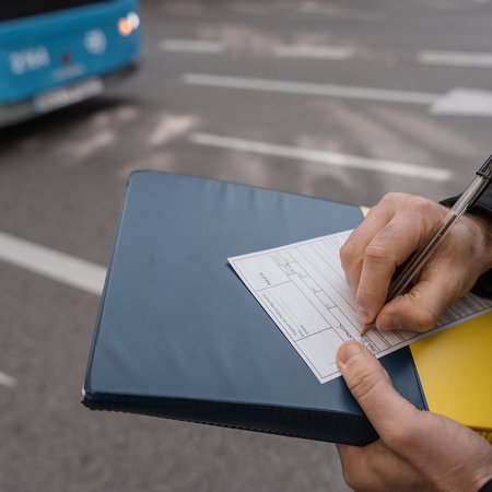 Traffic officer issuing a roadside penalty notice during a vehicle inspection in Spain.