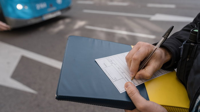 Traffic officer issuing a roadside penalty notice during a vehicle inspection in Spain.