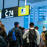 Passengers queue at a Ryanair boarding gate with cabin bags and backpacks before departure.
