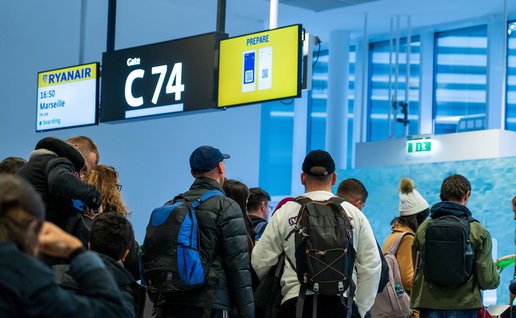 Passengers queue at a Ryanair boarding gate with cabin bags and backpacks before departure.