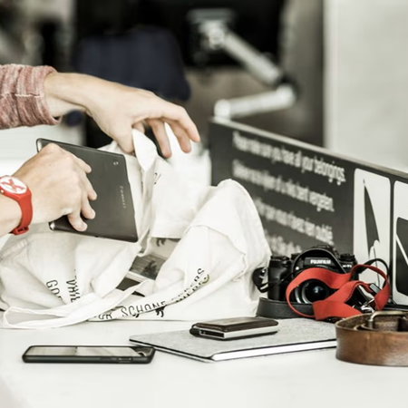 Passengers remove electronic devices and personal items from hand luggage during an airport security screening process.
