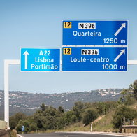 Faro, Portugal - September 16, 2018: blue road sign on A22 highway indicating the direction of Lisbon, Portugal on a summer day.