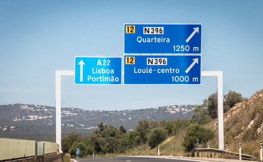 Faro, Portugal - September 16, 2018: blue road sign on A22 highway indicating the direction of Lisbon, Portugal on a summer day.
