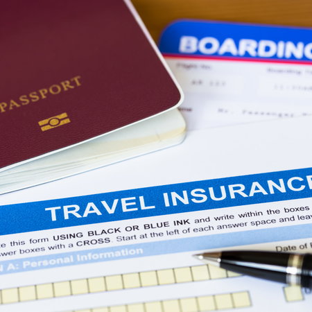 A passport with a boarding pass and travel insurance with a pen on a desk