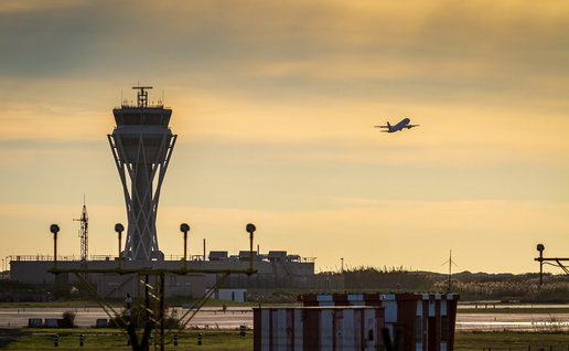 Sunset at an airport with air-traffic control tower and a plane taking off