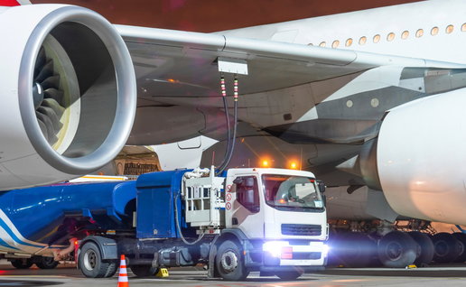 A truck under the wing of a plane refuelling it