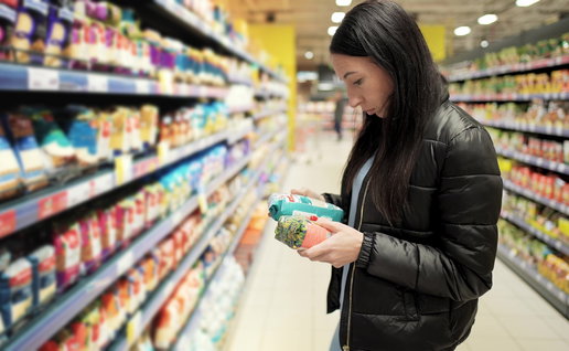 Woman in a supermarket looking at the ingredients on food