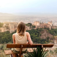 Woman sitting on a bench looking at the Alhambra palace