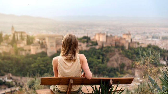 Woman sitting on a bench looking at the Alhambra palace