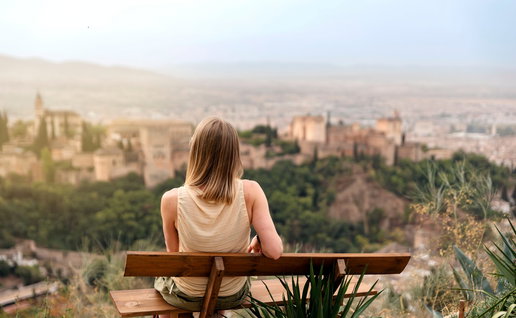 Woman sitting on a bench looking at the Alhambra palace